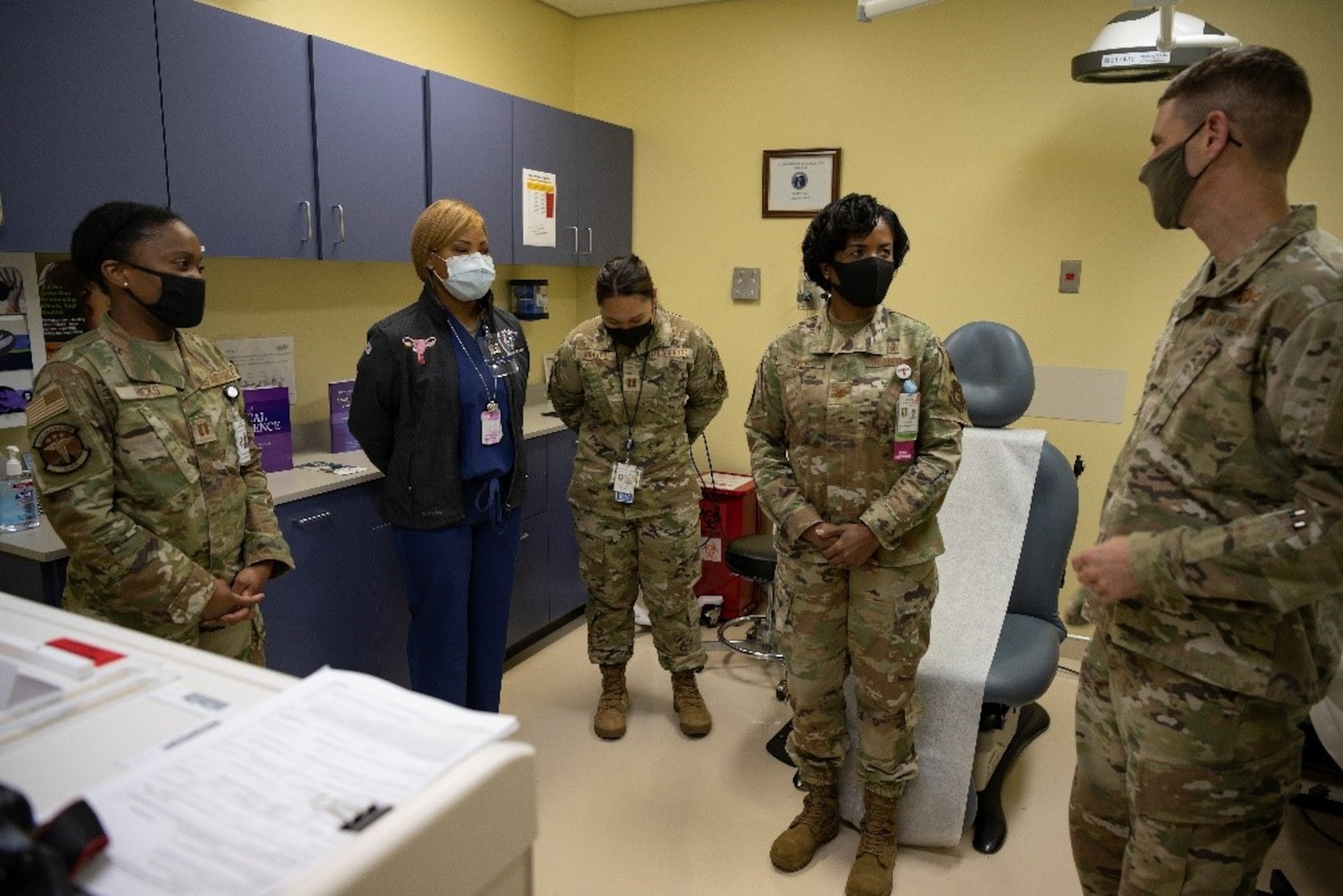 Five service members standing in a medical room talking.
