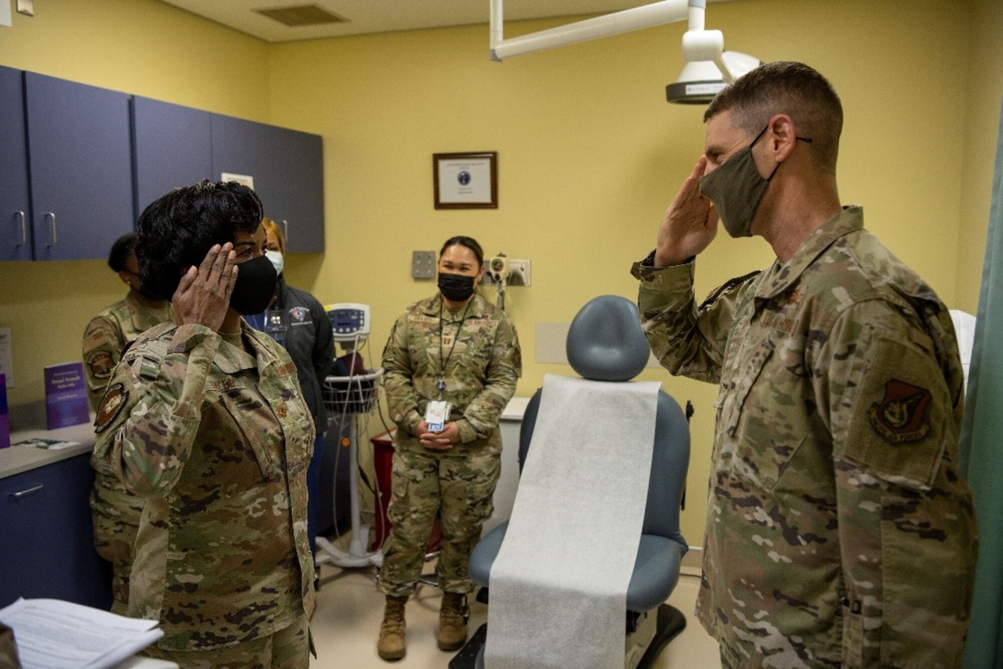 Service member in brown uniform salute another service member in brown uniform.