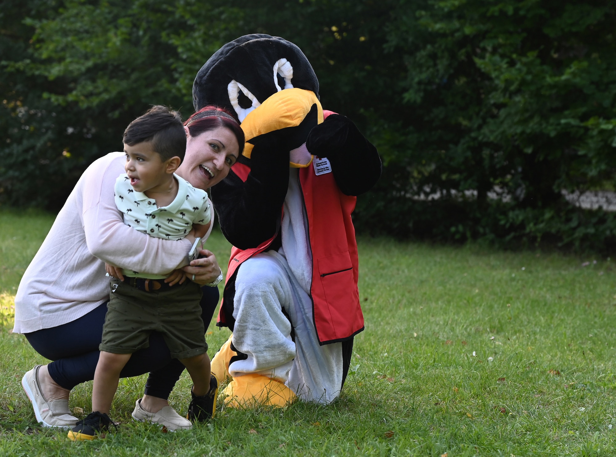Pedro the Penguin from the American Red Cross poses for a photo with a family at the Community Cares Partners Party in the Park event at the Vogelweh Military Complex, Germany, Aug. 12, 2021. Helping agencies from the Kaiserslautern Military Community came to the event to bring resources to service members and families. (U.S. Air Force photo by Senior Airman Thomas Karol)