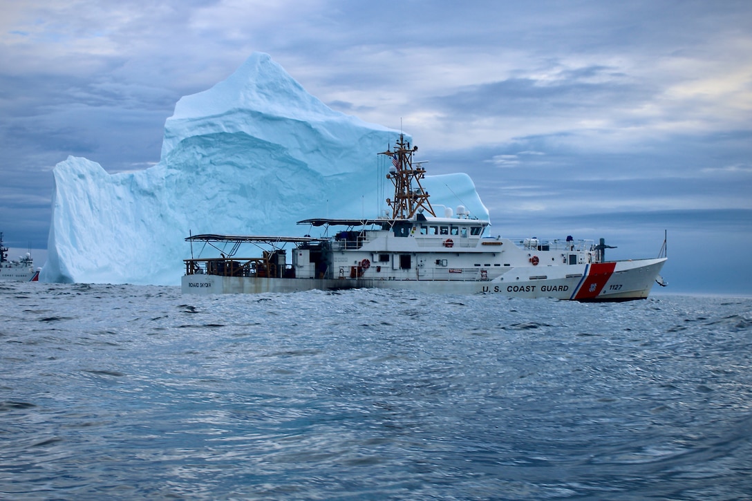A Coast Guard cutter maneuvers by an iceberg.