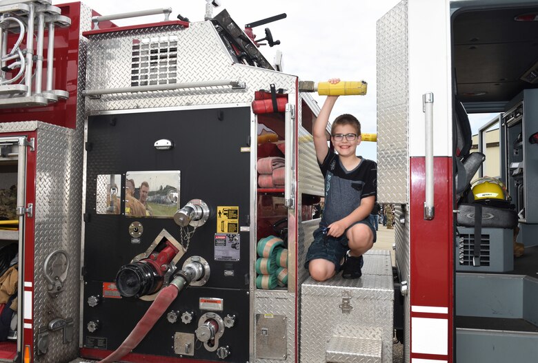 A Team Mildenhall child poses for a photo on a fire truck at the Diversity and Inclusion Day event at Royal Air Force Mildenhall, England, Aug. 13, 2021. The event included a variety of performances, food and informational booths, a fire truck, Humvee and various static aircraft. (U.S. Air Force photo by Karen Abeyasekere)