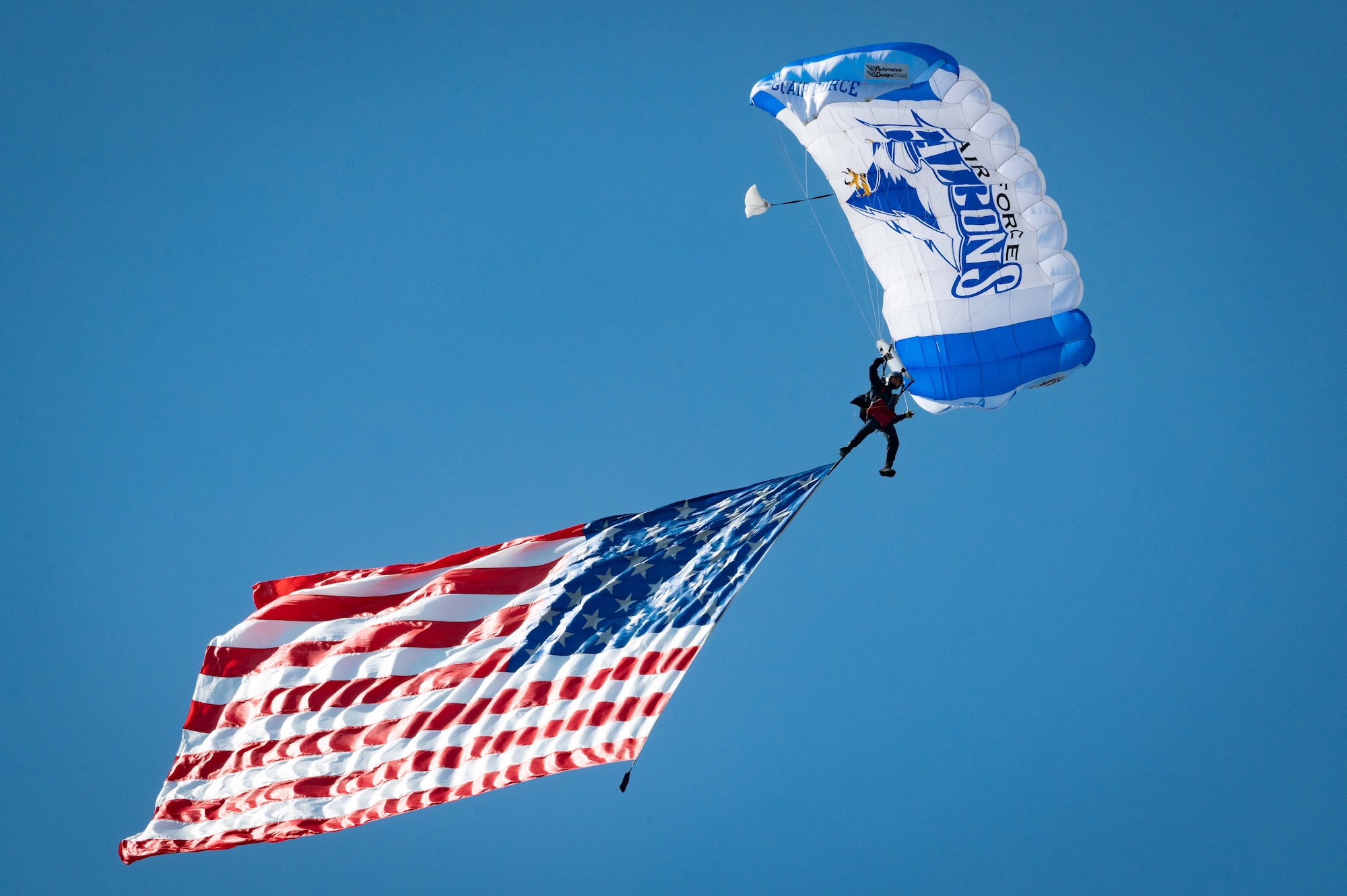 A U.S. Air Force Academy Wings of Blue parajumper glides while trailing the American flag during the 2021 Arctic Lightning Airshow at Eielson Air Force Base, Alaska, July 31, 2021.