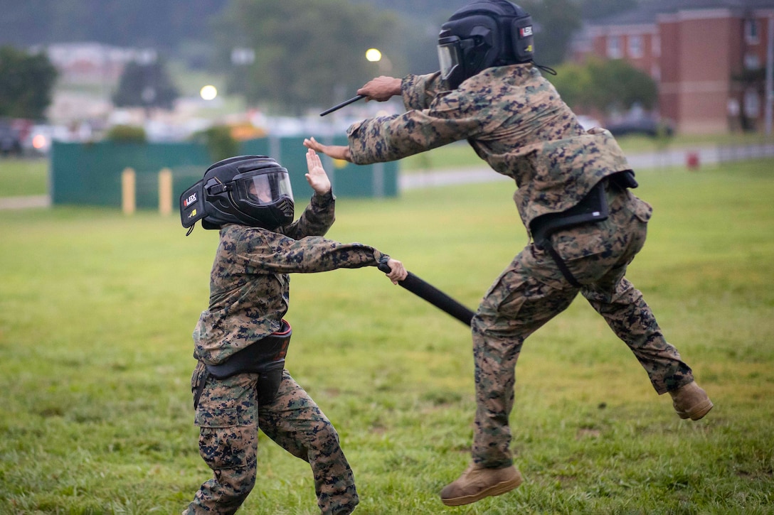 Two Marines spar in a field.