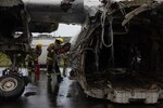 Firefighters cut into the side of a scrapped airplane.