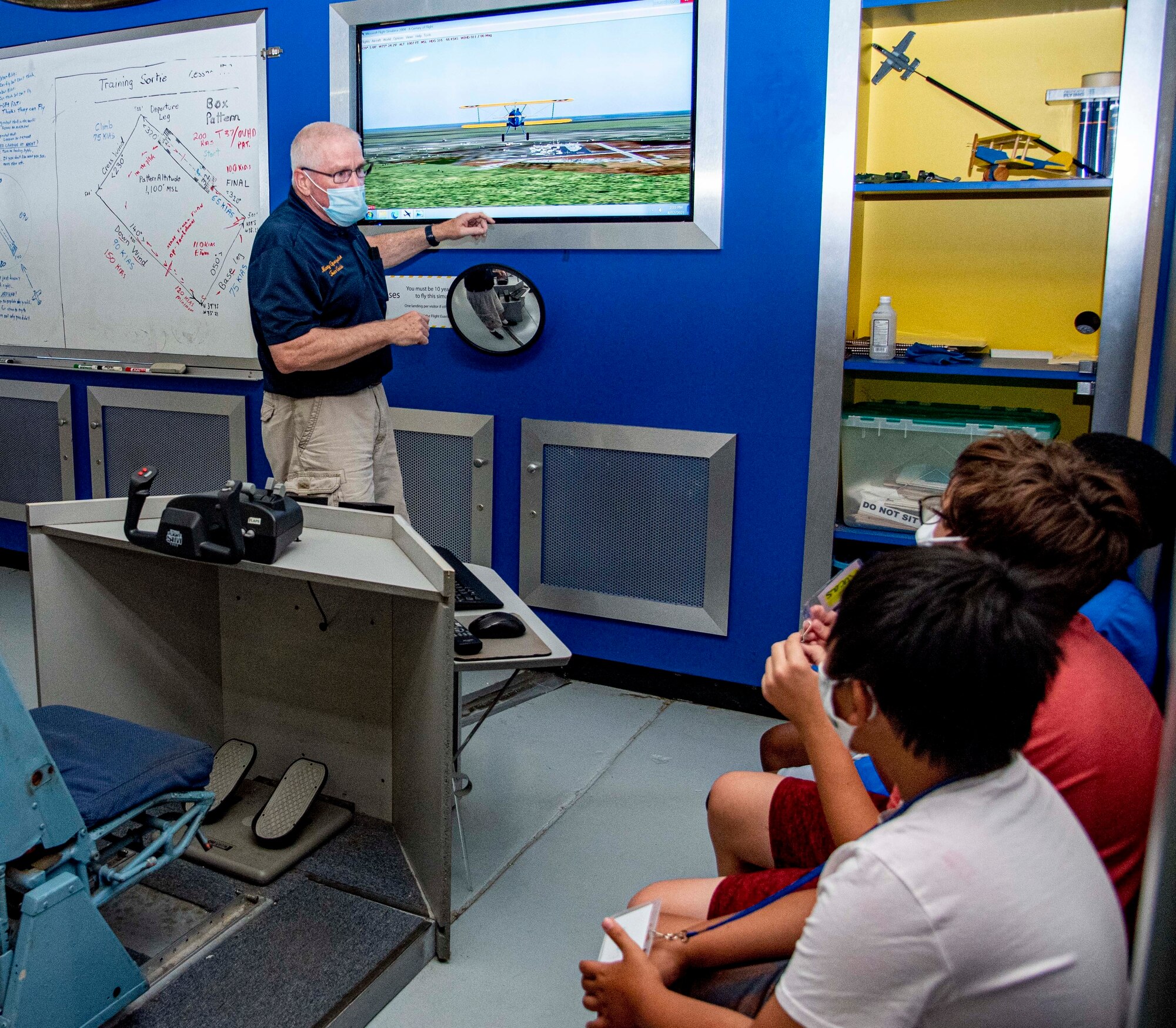 John Martin, Air Mobility Command Museum volunteer, explains to Summer Aviation Camp attendees how the flight simulator works at the AMC Museum on Dover Air Force Base, Delaware, Aug. 10, 2021. The attendees had the opportunity to fly a simulated Stearman Aircraft, fly in a Cessna with the Dover AFB Aero Club and interview Airmen and retirees and learn more about the military. This year’s summer camp utilized Quonset Hut classrooms created during last year’s pandemic and can also be used by homeschooling parents. (U.S. Air Force photo by Tech. Sgt. Nicole Leidholm)