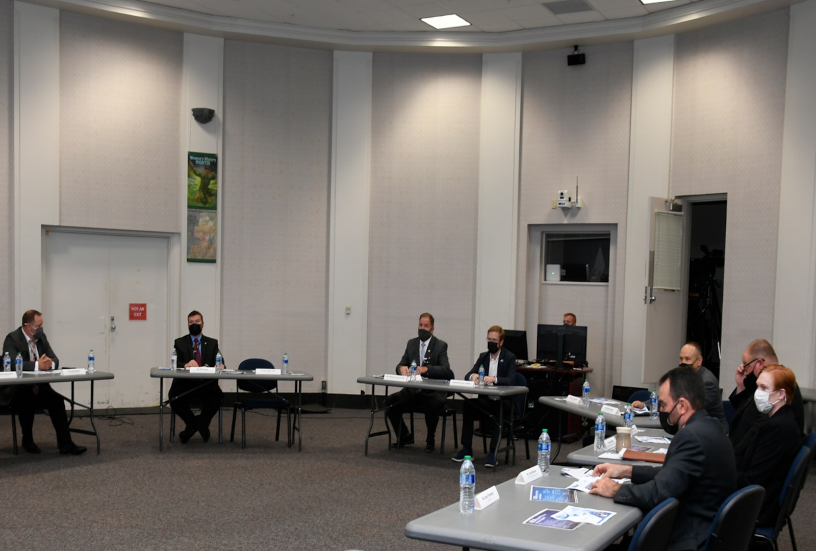 Men and women sit at tables in a conference room.