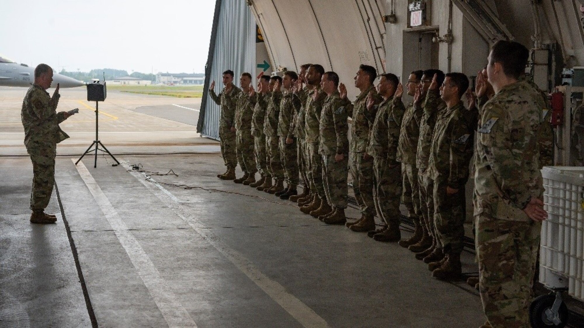 Twenty-three military members raise right hand and recite an oath.