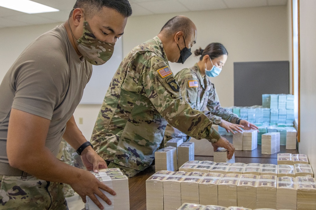 From left to right, Capt. Cynjun Salinas, Lt. Col. Luke Ahn and Spc. Saralin Moon, 326th Financial Management Support Center Soldiers, stack simulated currency after moving their operation in less than two hours during Diamond Saber at Fort McCoy, Wisconsin, Aug. 14, 2021. Diamond Saber is a U.S. Army Reserve-led exercise that incorporates participation from all components and joint services, and it prepares finance and comptroller Soldiers on the warfighting functions of funding the force, payment support, disbursing operations, accounting, fiscal stewardship, auditability and data analytics. (U.S. Army photo by Mark R. W. Orders-Woempner)