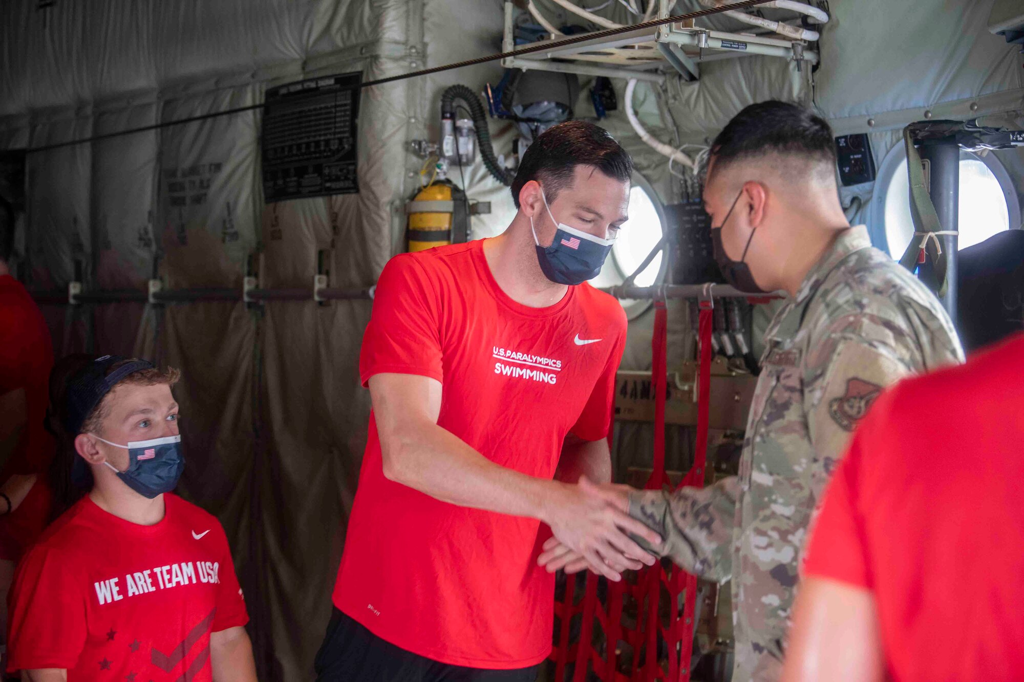U.S. Paralympians shake hands with an Airman, thanking him for his service, while touring a C-130J Super Hercules at Yokota Air Base, Japan, Aug. 18, 2021.