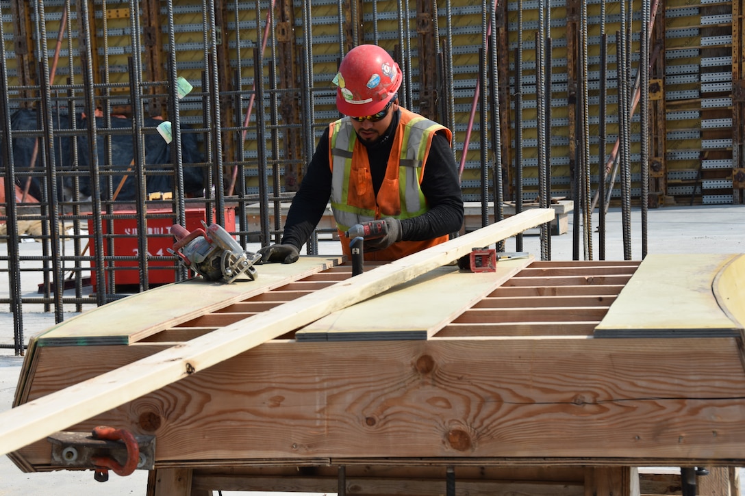 A man in a hard hat and reflective vest at a construction site.