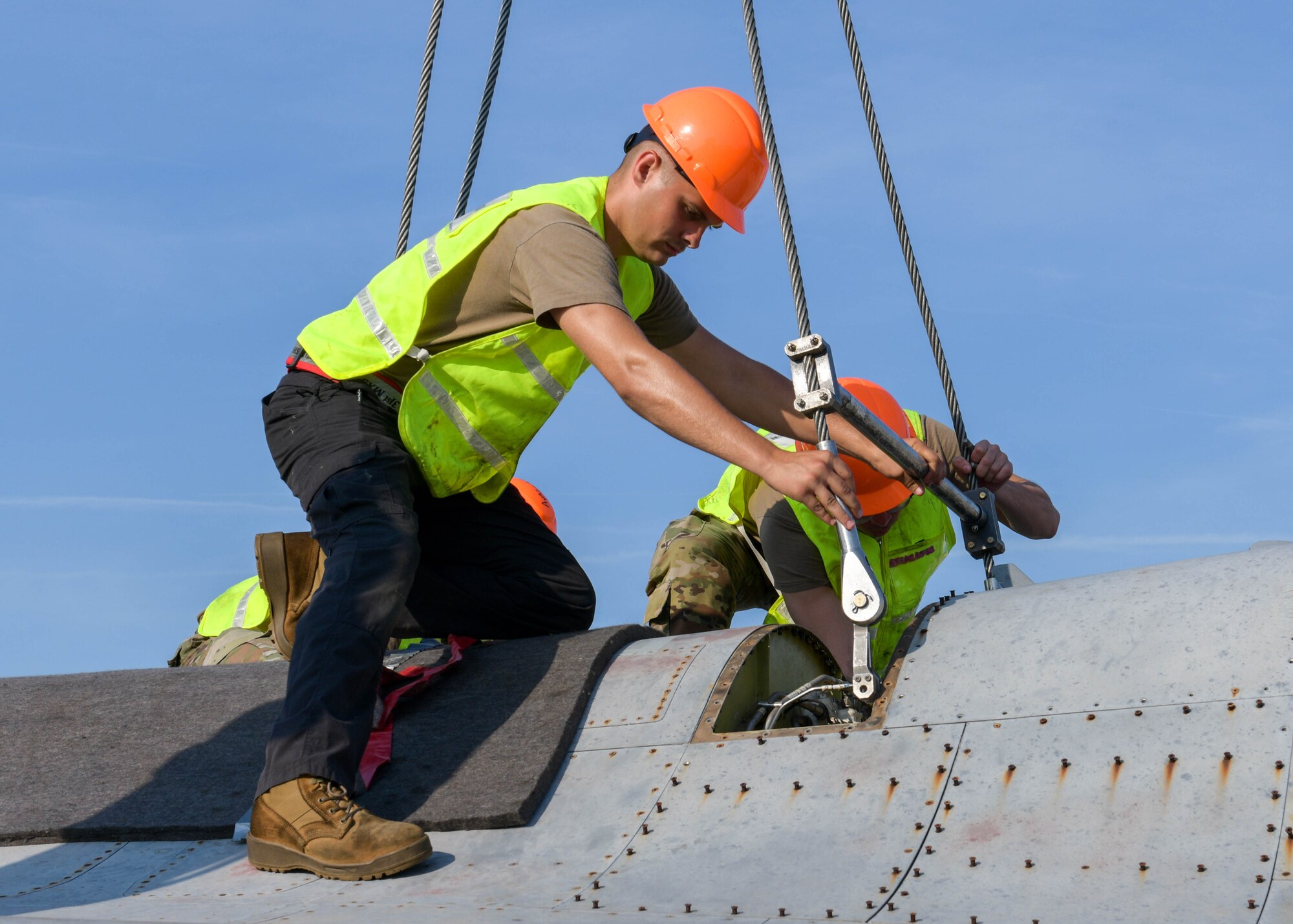 Senior Airman Hunter Clark, 31st Maintenance Squadron transient alert journeyman, attaches a lifting sling onto a U.S. Air Force  F-16 Fighting Falcon at Aviano Air Base, Italy, Aug. 13, 2021. Airmen assigned to the 31st MXS and 52nd MXS performed an annual Crash, Damaged or Disabled Aircraft Recovery (CDDAR) lift certification to recertify on the correct procedures of lifting an aircraft during an emergency. The lifting sling was used to keep the F-16 stable during the lift. (U.S. Air Force photo by Senior Airman Brooke Moeder)