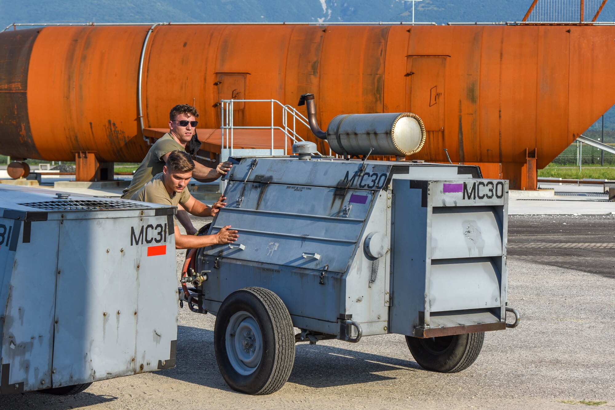 Senior Airman Hunter Clark, left, and Senior Airman Jarrett Janak, 31st Maintenance Squadron (MXS) transient alert journeymen, push equipment in preparation for a Crash, Damaged or Disabled Aircraft Recovery (CDDAR) lift certification at Aviano Air Base, Italy, Aug. 13, 2021. The 31st MXS and 52nd MXS, Spangdahlem Air Base, Germany, participated in an annual CDDAR training to recertify on qualifications. The 31st MXS provides accessory maintenance, avionics, periodic phase inspections, fabrication, and aerospace ground equipment for assigned aircraft. (U.S. Air Force photo by Senior Airman Brooke Moeder)