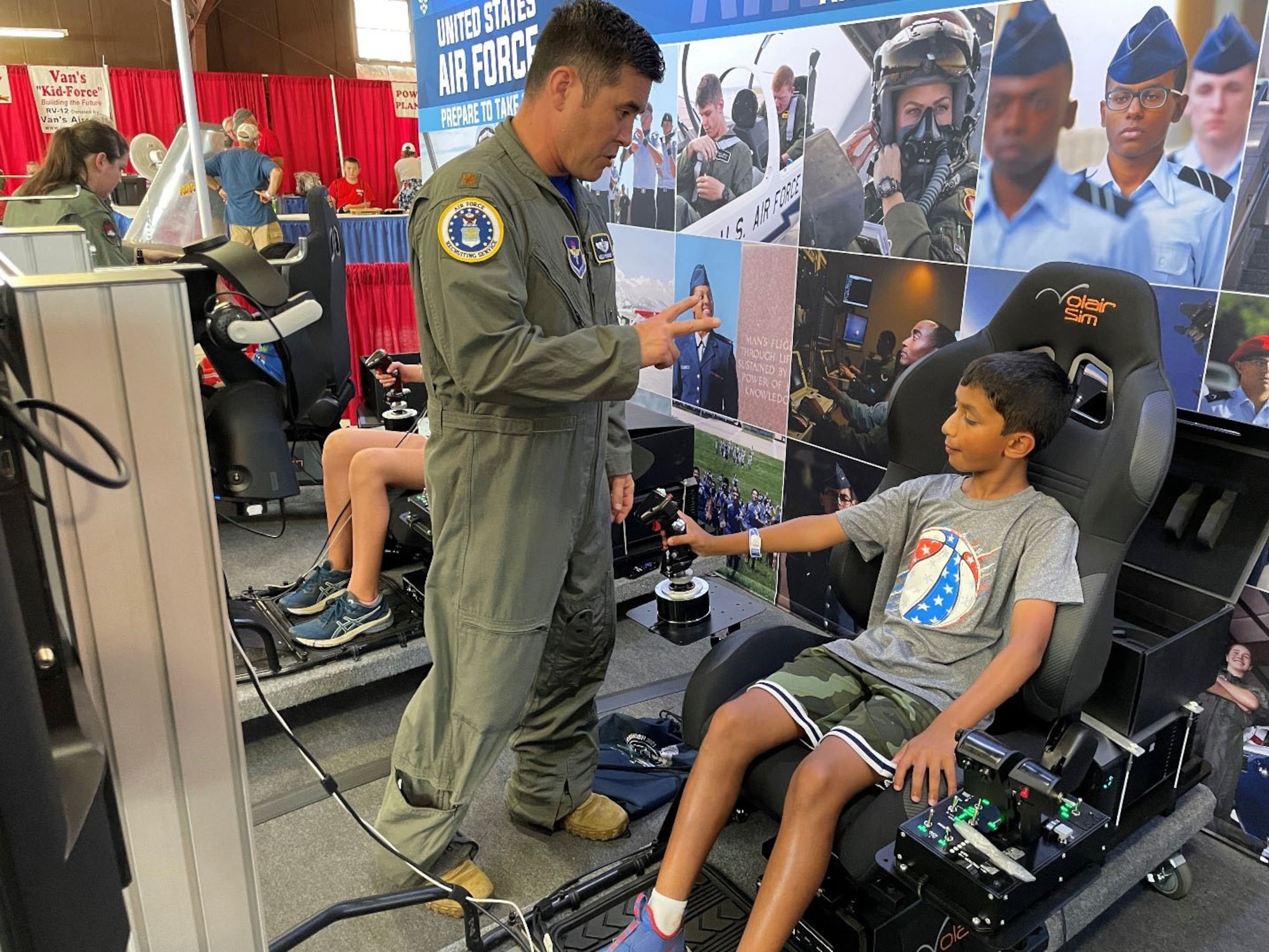 Maj. Kelly McNerney with Air Force Recruiting Service Detachment 1, instructs a student attending the Experimental Aircraft Association (EAA) AirVenture Air Show on the best practices for operating the flight simulator at Oshkosh, Wis., July 26, 2021.