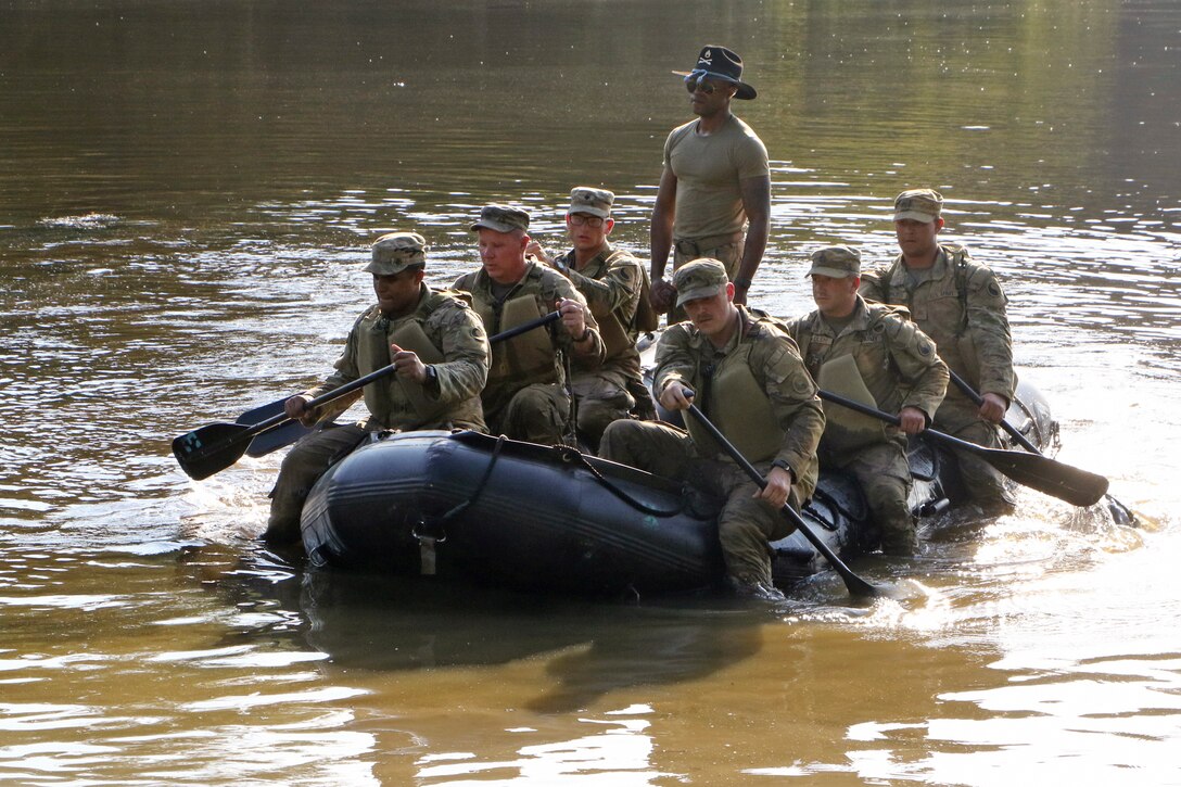 A group of soldiers ride in an inflatable boat.