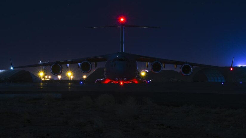 A large military plane is lit up at night.