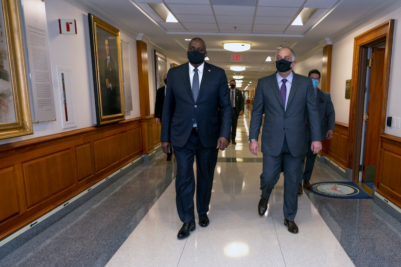 Two men walk down a hallway.
