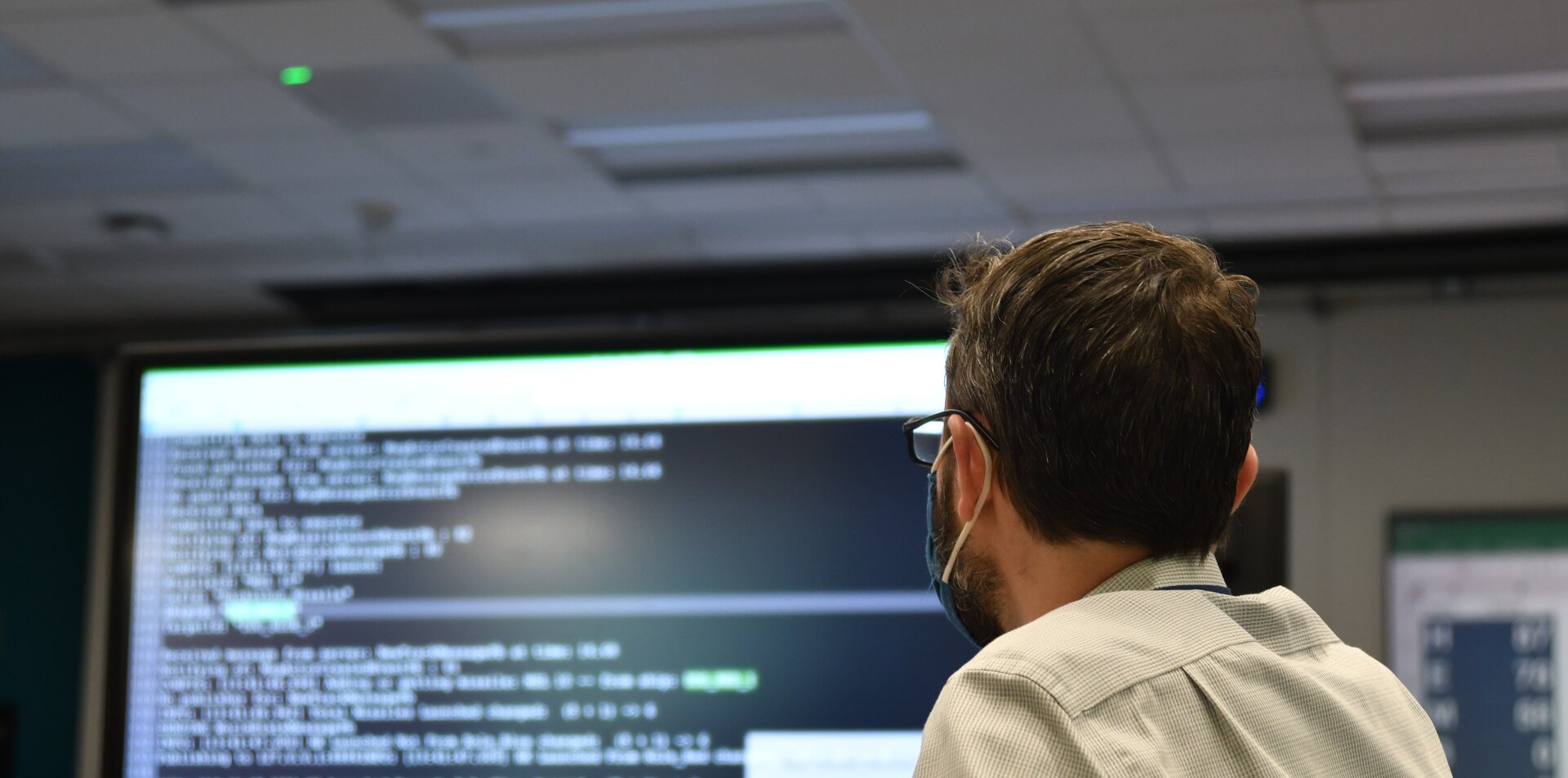 IMAGE: A Naval Surface Warfare Center Dahlgren Division engineer looks on while his teammate plugs their algorithm into the Joint Cognitive Operational Research Environment during the NSWCDD Innovation Lab’s wargaming hackathon on Aug. 11.