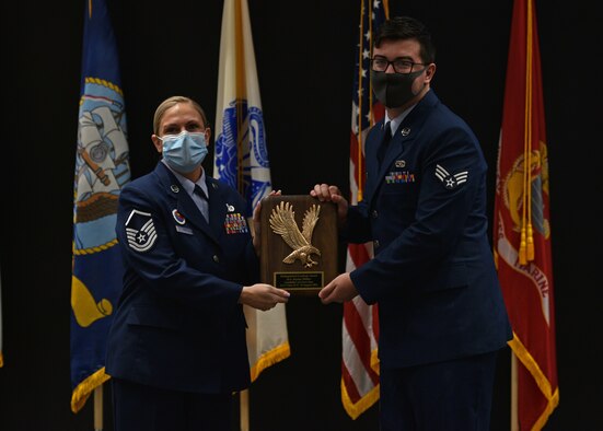 U.S. Air Force Master Sgt. Elizabeth Mann, Goodfellow Airman Leadership School commandant, presents Senior Airman Jaylan Miller, 47th Flying Training Wing aircrew egress technician, the Distinguished Graduate award during Miller’s Airman Leadership School graduation ceremony on Goodfellow Air Force Base, Texas, Aug. 19, 2021. The Distinguished Graduate Award recognizes the student who is in the top 10 percent of their class based on performance tasks, peer stratifications and the capstone exercise. (U.S. Air Force photo by Senior Airman Ashley Thrash)