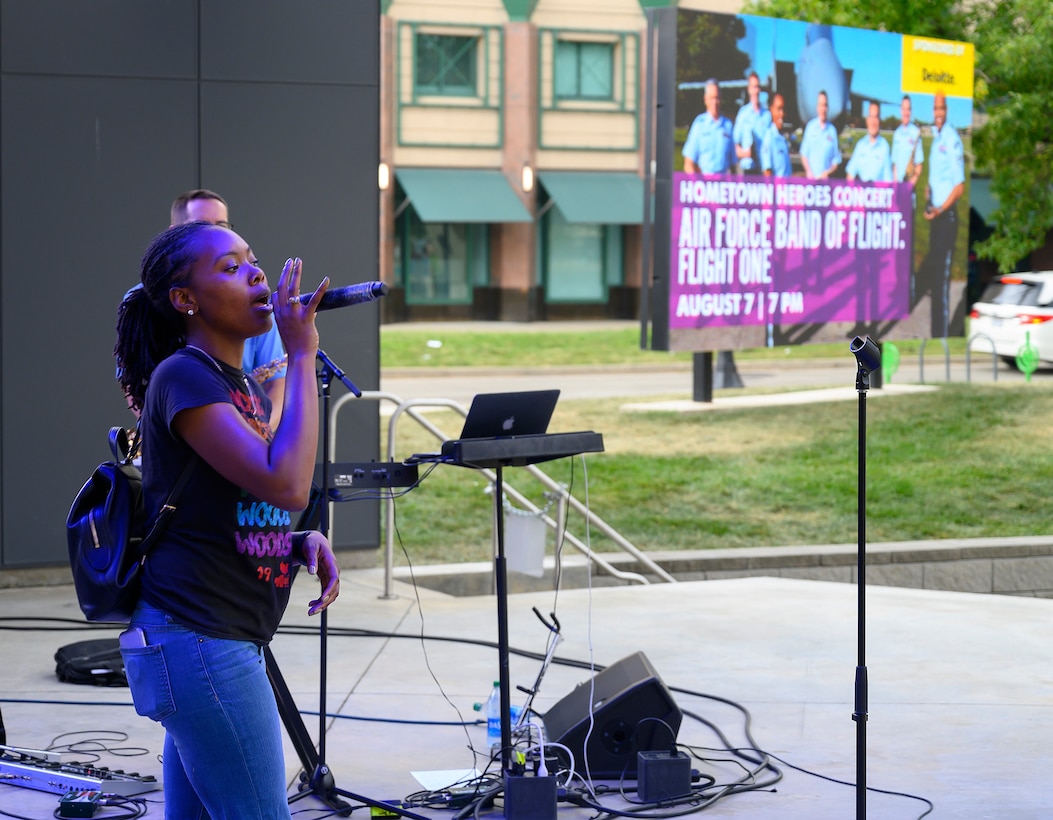Senior Airman MeLan Smartt, Air Force Band of Flight’s Flight One vocalist, does her sound check on the stage of Levitt Pavilion in Dayton, Ohio, the afternoon of Aug. 7, 2021, as an electronic billboard advertises that night’s show.  (U.S. Air Force photo by R.J. Oriez)