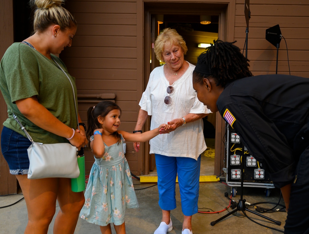 Senior Airman MeLan Smartt, Flight One vocalist, visits with Maelyn Little, 4, her aunt, Sami Little, and grandmother, Ellen Little, following the Air Force rock band’s concert Aug. 13, 2021, at Centerville Community Amphitheater in Stubbs Park, Centerville, Ohio. As part of the group’s outreach function, band members visit with the audience after each show. (U.S. Air Force photo by R.J. Oriez)