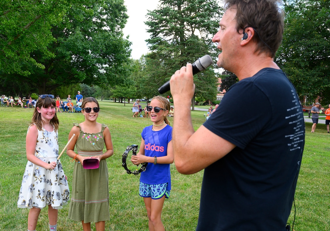 eff Stevens, lead singer for Stranger, gets (from left) Amelia Hunter, 9, Ella Arnold, 11, and Hannah Greiner, 10, to accompany him on a song as he and his band perform at a block party Aug. 12, 2021, put on by the 88th Force Support Squadron in the historic Brick Quarters housing area at Wright-Patterson Air Force Base, Ohio. This was the second of three parties this summer, with the last one scheduled for Aug. 26. (U.S. Air Force photo by R.J. Oriez)