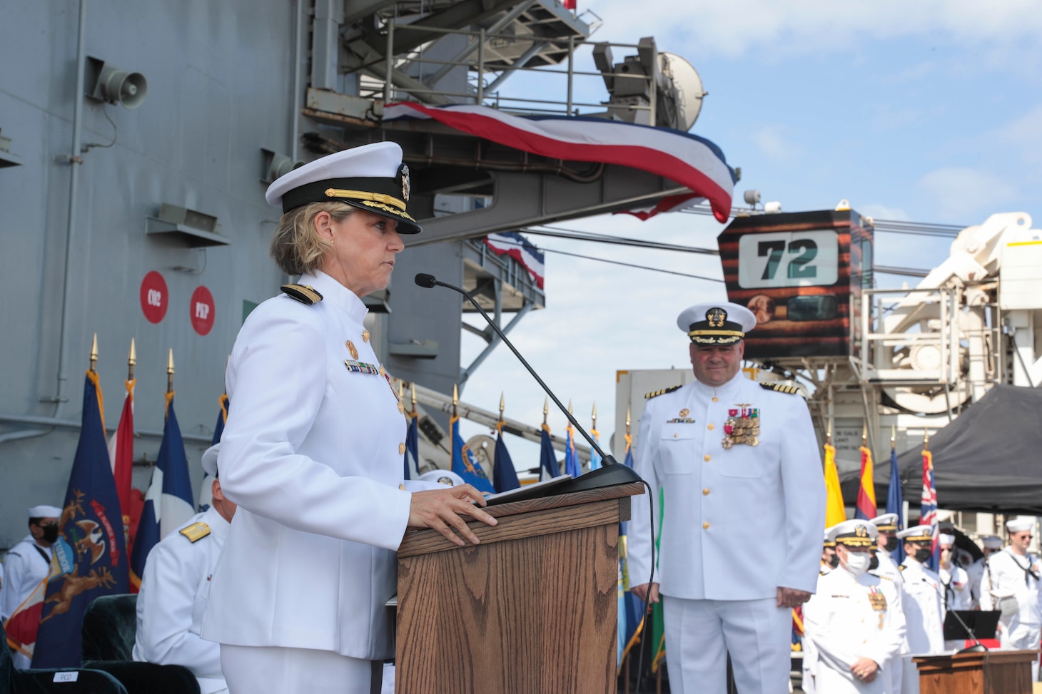 Capt. Amy Bauernschmidt,  incoming commanding officer of the aircraft carrier USS Abraham Lincoln (CVN 72), reads her orders during a change of command ceremony held on the flight deck.