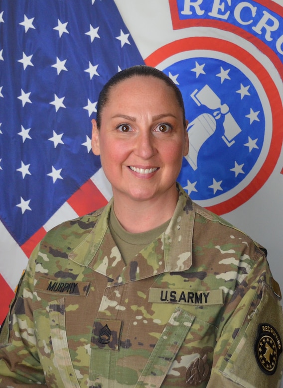 photo of a woman in uniform standing in front of flags.