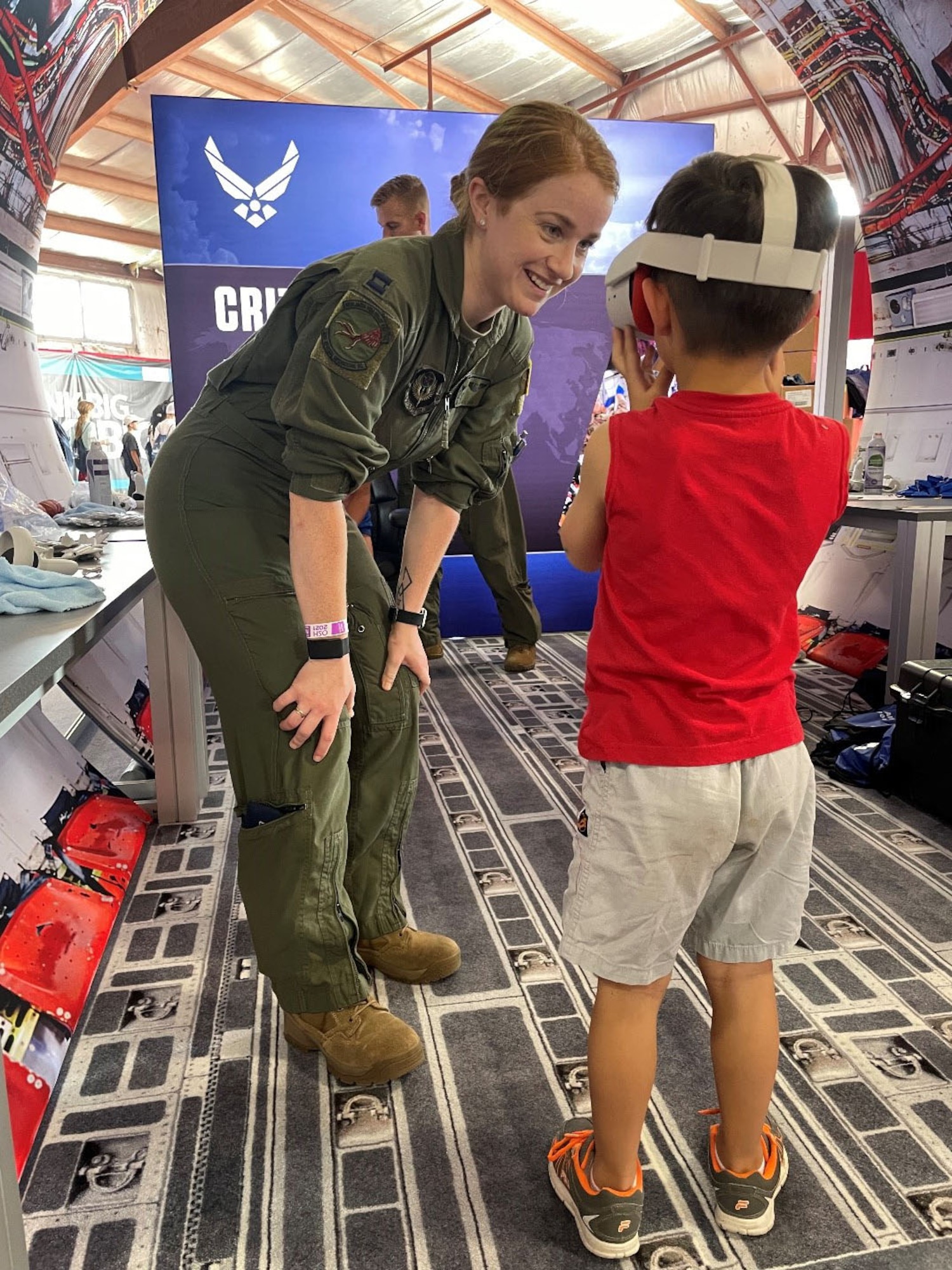 An RPA pilot, shows a student attending the Experimental Aircraft Association (EAA) AirVenture Air Show what an experience it is to operate an F-16 Fighting Falcon from the perspective of a 360 degree video through a virtual reality headset at Oshkosh, Wis., July 26, 2021.
