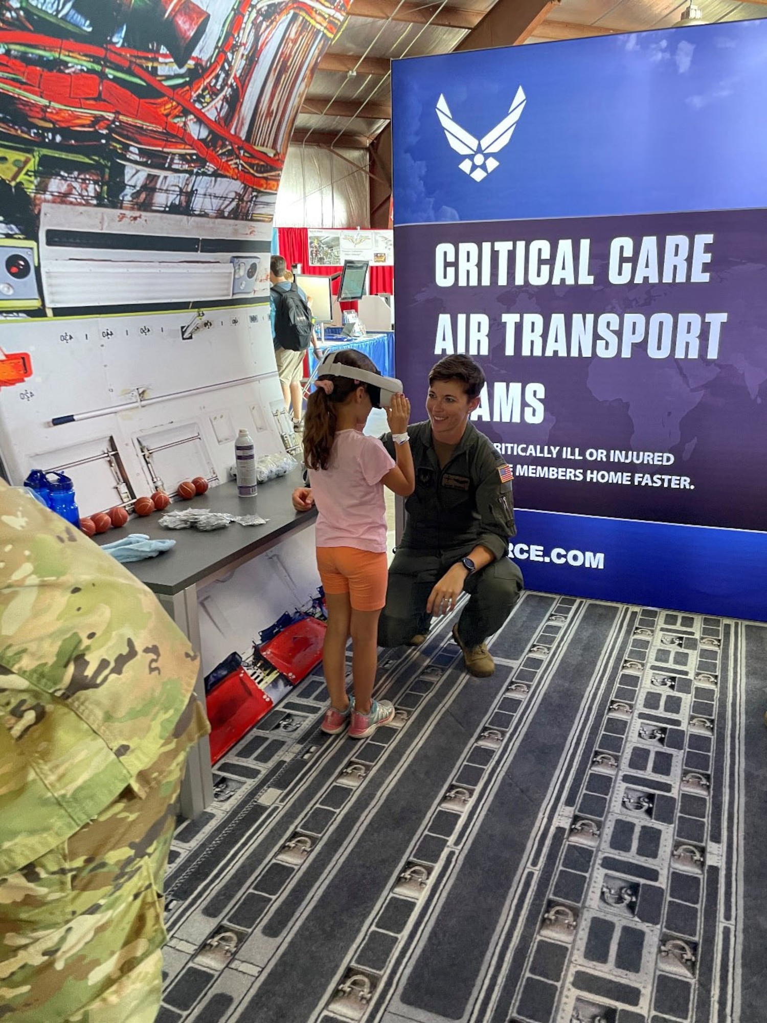 Capt. Blaine Driscoll, a U-28 Combat Systems Officer assigned to the 318th Special Operations Squadron, shows a student attending the Experimental Aircraft Association (EAA) AirVenture Air Show what an experience it is to operate an F-22 Raptor from the perspective of a 360 degree video through a virtual reality headset at Oshkosh, Wis., July 26, 2021.