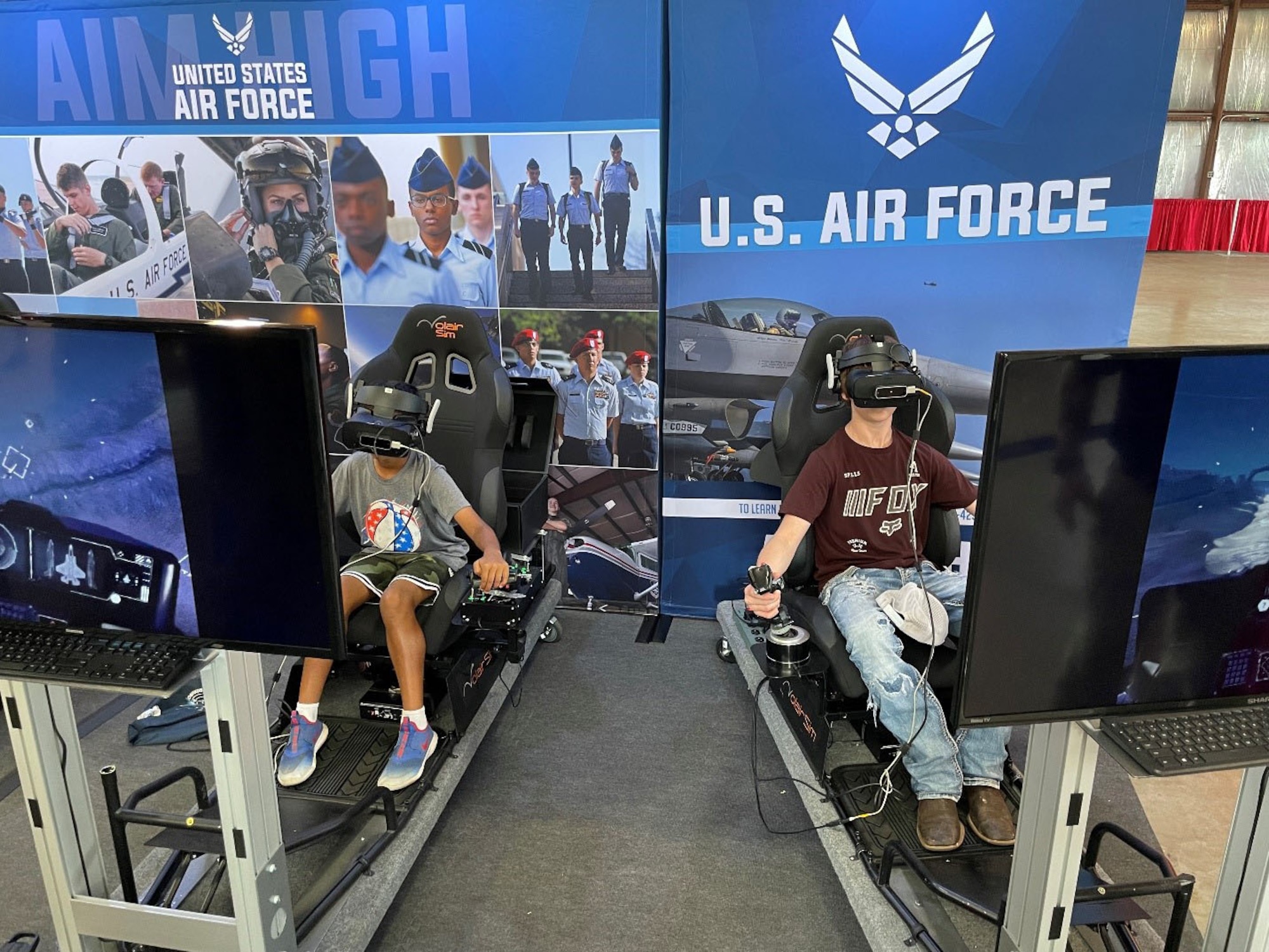Two students compete with a flight simulator game sponsored by the U.S. Air Force Recruiting Service Detachment 1 at the Experimental Aircraft Association (EAA) AirVenture Air Show at Oshkosh, Wis., July 26, 2021.
