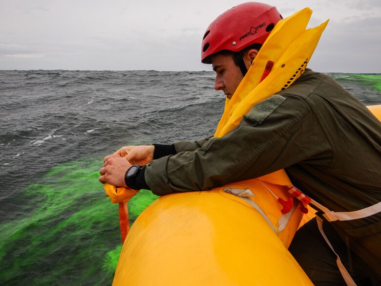 Staff Sgt. Paul Thomason, 436th Operational Support Squadron survival, evasion, resistance and escape flight augmentee, puts sea dye in seawater to signal a C-17 Globemaster III near Coast Guard Station Indian River Inlet, Delaware, Aug. 4, 2021. The crew aboard the life raft used several signaling devices like the CSEL radio, sea dye, life raft canopy and flare to vector the C-17 to their location during the exercise. (U.S. Air Force photo by Senior Airman Marco A. Gomez)