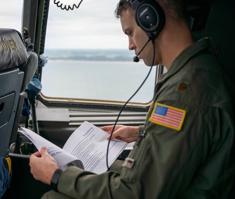 Maj. Daniel Velo, 3rd Airlift Squadron pilot, reads on-scene commander information during Exercise Castaway aboard a C-17 Globemaster III over the Atlantic Ocean, Aug. 4, 2021. Exercise Castaway is an interagency training exercise that brought Airmen from Dover AFB and two coast guard stations, Coast Guard Air Station Atlantic City, New Jersey, and Coast Guard Station Indian River Inlet, Delaware, together to train local search and rescue procedures. (U.S. Air Force photo by Senior Airman Faith Schaefer)