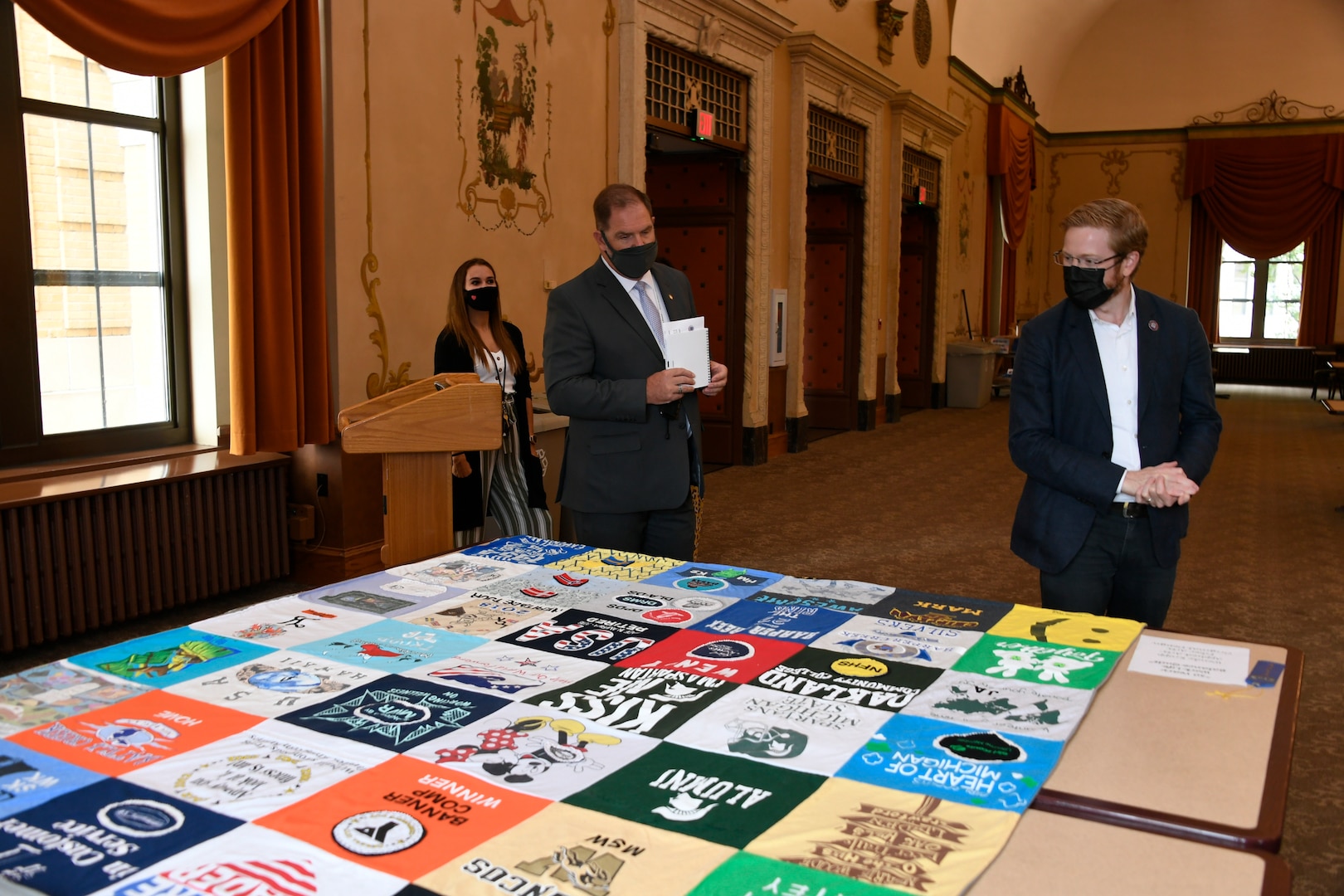 Onlookers examine a quilt that is part of an art display.