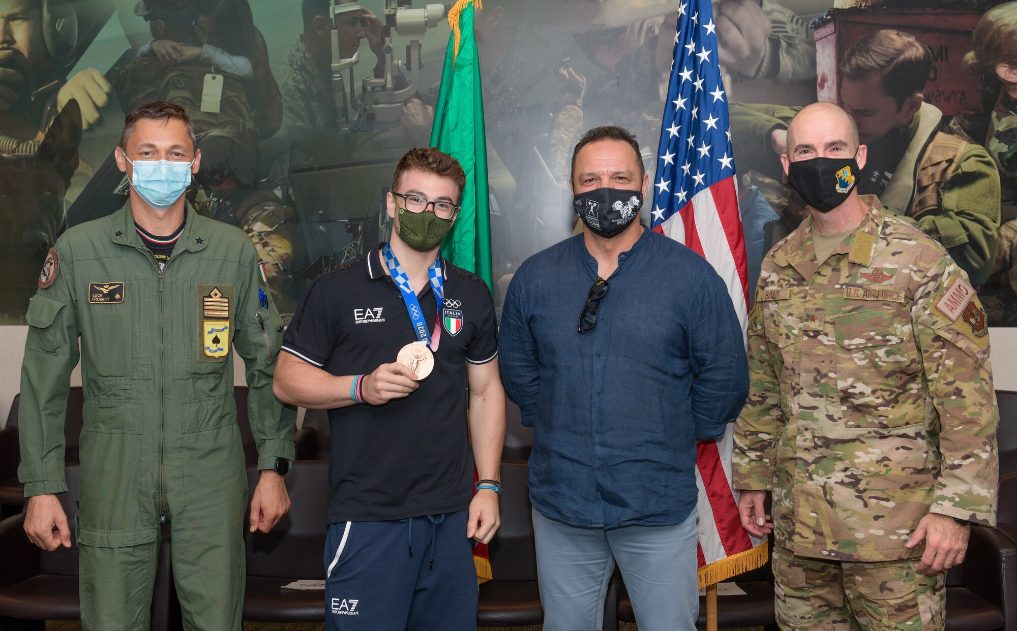 Italian air force (ITAF) Col. Luca Crovatti, ITAF base commander, left, Mirko and Giorgio Zanni, middle, and U.S. Air Force Brig. Gen. Jason Bailey, 31st Fighter Wing commander, right, pose for a photo at Aviano Air Base, Italy, Aug. 19, 2021. Mirko, a 2020 Summer Olympics weightlifting bronze medalist winner, attended a powerlifting competition and toured different facilities on base including the Air Control Tower and an F-16 Fighting Falcon. (U.S. Air Force photo by Senior Airman Brooke Moeder)