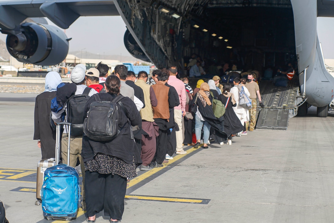 A line of evacuees waits to board a military aircraft.