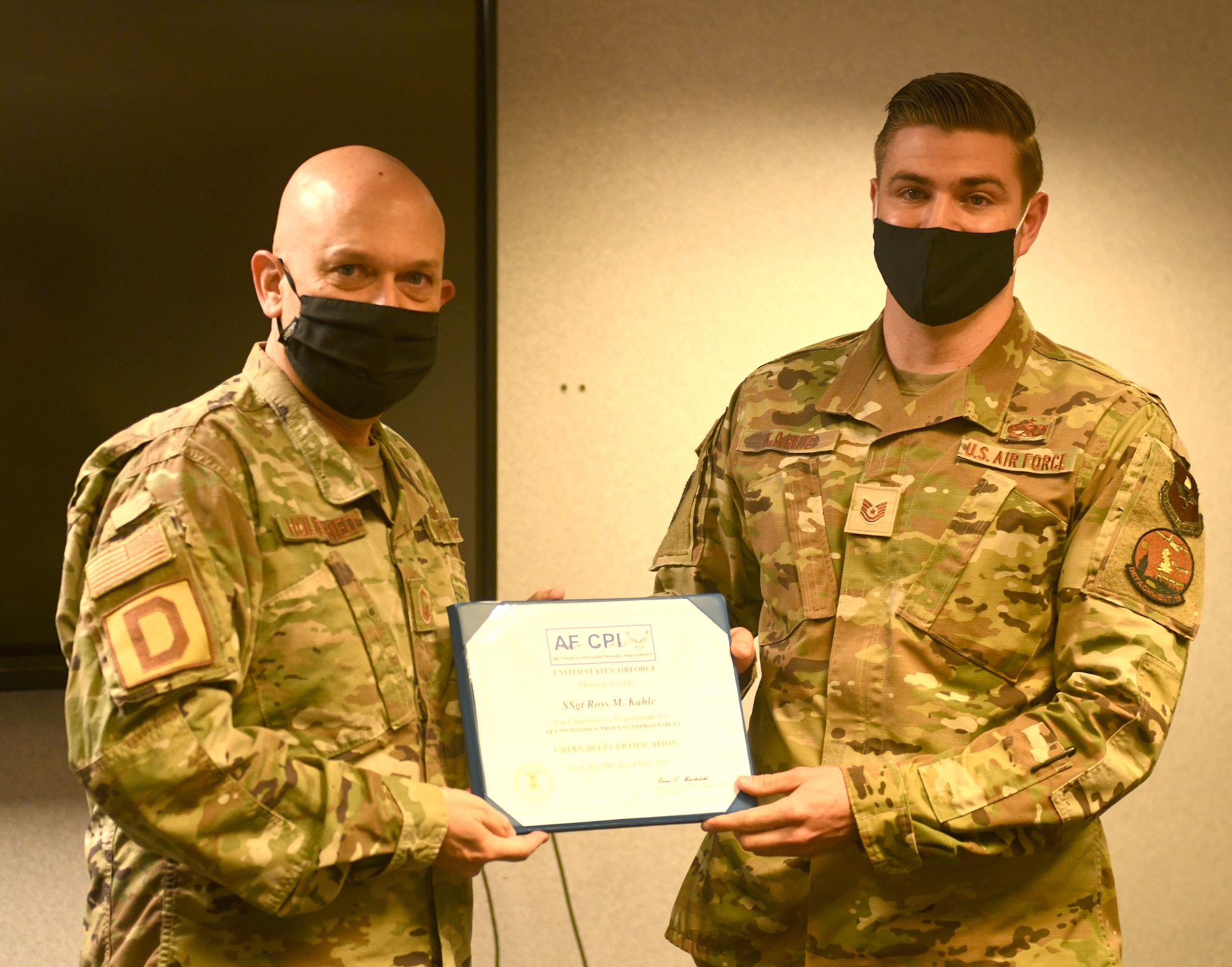 U.S. Air Force Senior Master Sgt. Stephen Holdenried, 100th Air Refueling Wing Continuous Process Improvement process manager presents a framed copy of a Green Belt certification project to U.S. Air Force Tech. Sgt. Ross Kahle, 373rd Training Squadron, Detachment 19 Aerospace Ground Equipment instructor, at Royal Air Force Mildenhall Aug. 18, 2021. Kahle instigated the project and put together a team to find issues and solve problems in his training squadron as part of his certification process, enabling him to become fully certified in Green Belt training. (U.S. Air Force photo by Tech. Sgt. Mackenzie Mendez)