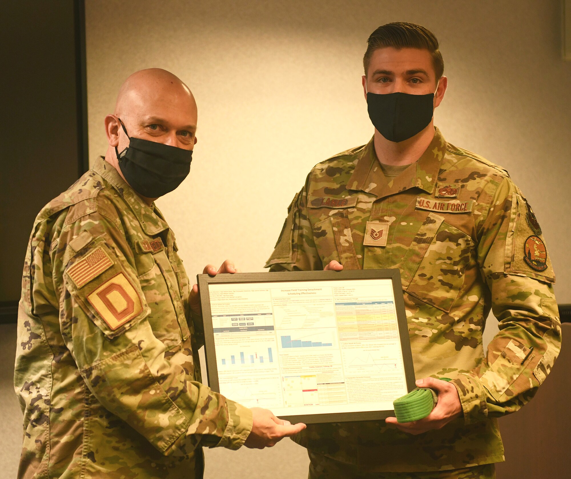 U.S. Air Force Senior Master Sgt. Stephen Holdenried, 100th Air Refueling Wing Continuous Process Improvement process manager presents a certificate for Green Belt certification to U.S. Air Force Tech. Sgt. Ross Kahle, 373rd Training Squadron, Detachment 19 Aerospace Ground Equipment instructor, at Royal Air Force Mildenhall Aug. 18, 2021. Kahle is one of less than two percent of those in the Air Force to be fully certified in Green Belt training. (U.S. Air Force photo by Tech. Sgt. Mackenzie Mendez)