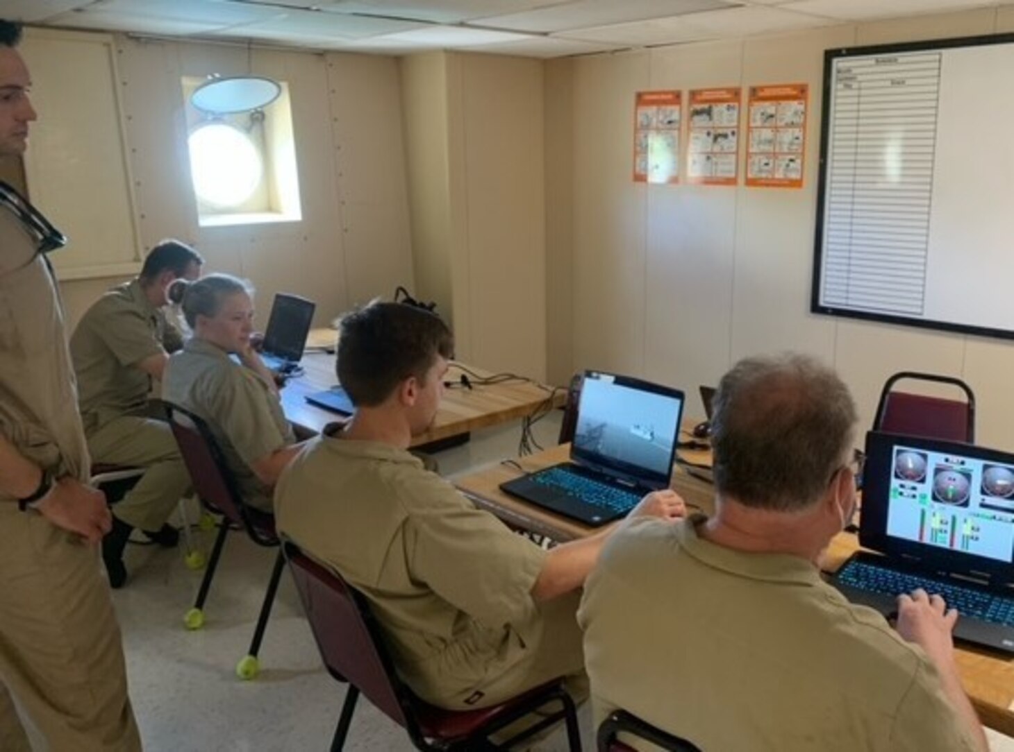 From left, Maine Maritime Academy Cadets Matthew Chase and Elizabeth Labbe, Third Officer Alexander Huff and Second Officer Todd Hollingworth, along with Third Officer Richard Leach, standing, participate in bridge resource management aboard USNS Tippecanoe (T-AO 199) while in port Guam, June 25-27.