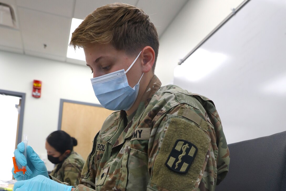 A soldier puts vaccine into a syringe.