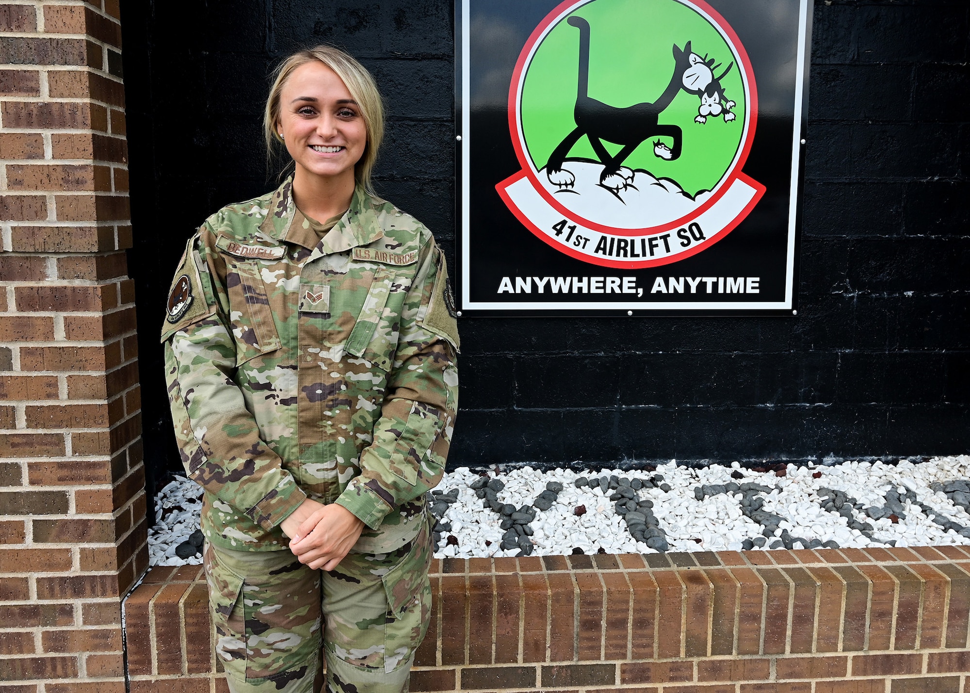 A woman stands in front of a sign with the 41st Airlift Squadron's logo on it.