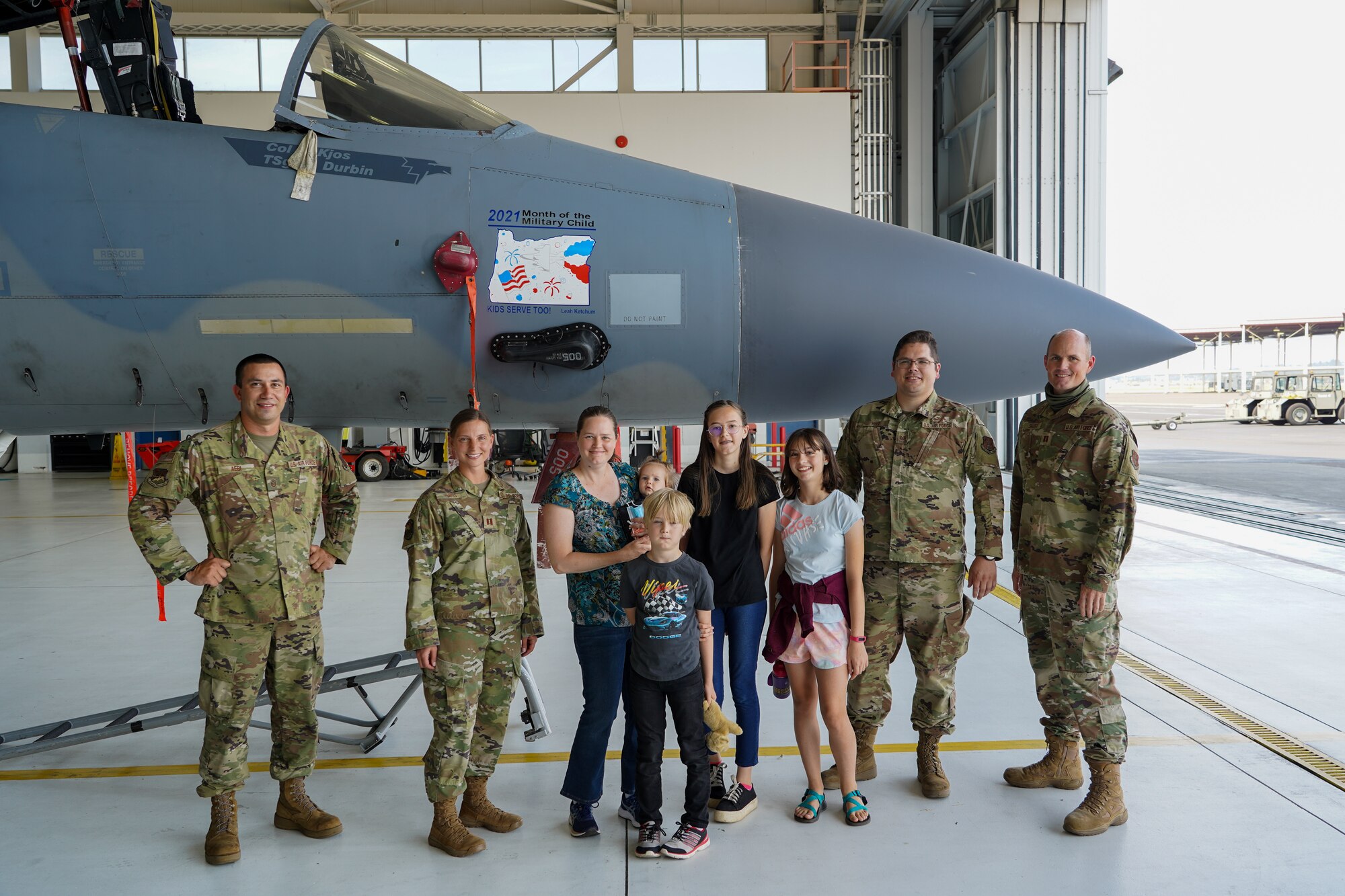 Leah Ketchum and her family along with members of the 142nd Maintenance Group pose for a photo in front of a 142nd Wing F-15 Eagle that now displays her artwork on its nose on August 12, 2021 in Portland, Ore. The 142nd Wing and the 173rd Fighter Wing both held contests in support of Month of the Military Child in which each wing chose one winner to have their designs applied to fighter jets at their respective wings. (U.S. Air National Guard Photo by Staff. Sgt. Alexander Frank)