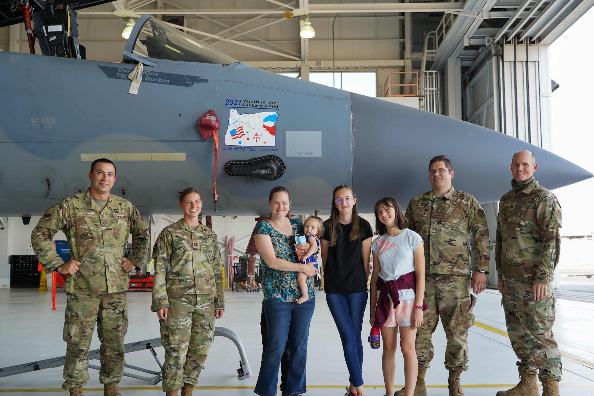 Leah Ketchum and her family along with members of the 142nd Maintenance Group pose for a photo in front of a 142nd Wing F-15 Eagle that now displays her artwork on its nose on August 12, 2021 in Portland, Ore. The 142nd Wing and the 173rd Fighter Wing both held contests in support of Month of the Military Child in which each wing chose one winner to have their designs applied to fighter jets at their respective wings. (U.S. Air National Guard Photo by Staff. Sgt. Alexander Frank)