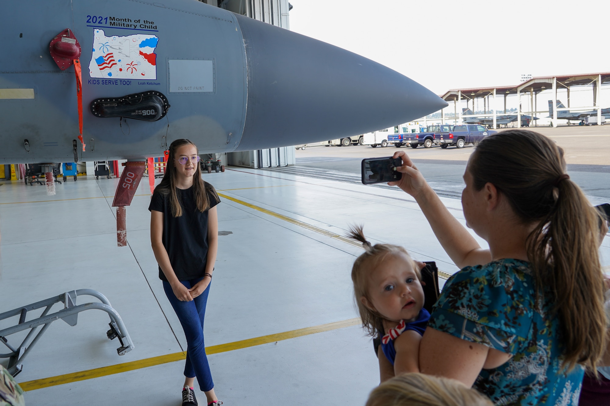 Leah Ketchum poses for a photo in front of a 142nd Wing F-15 Eagle that now displays her artwork on its nose on August 12, 2021 in Portland, Ore. The 142nd Wing and the 173rd Fighter Wing both held contests in support of Month of the Military Child in which each wing chose one winner to have their designs applied to fighter jets at their respective wings. (U.S. Air National Guard Photo by Staff. Sgt. Alexander Frank)