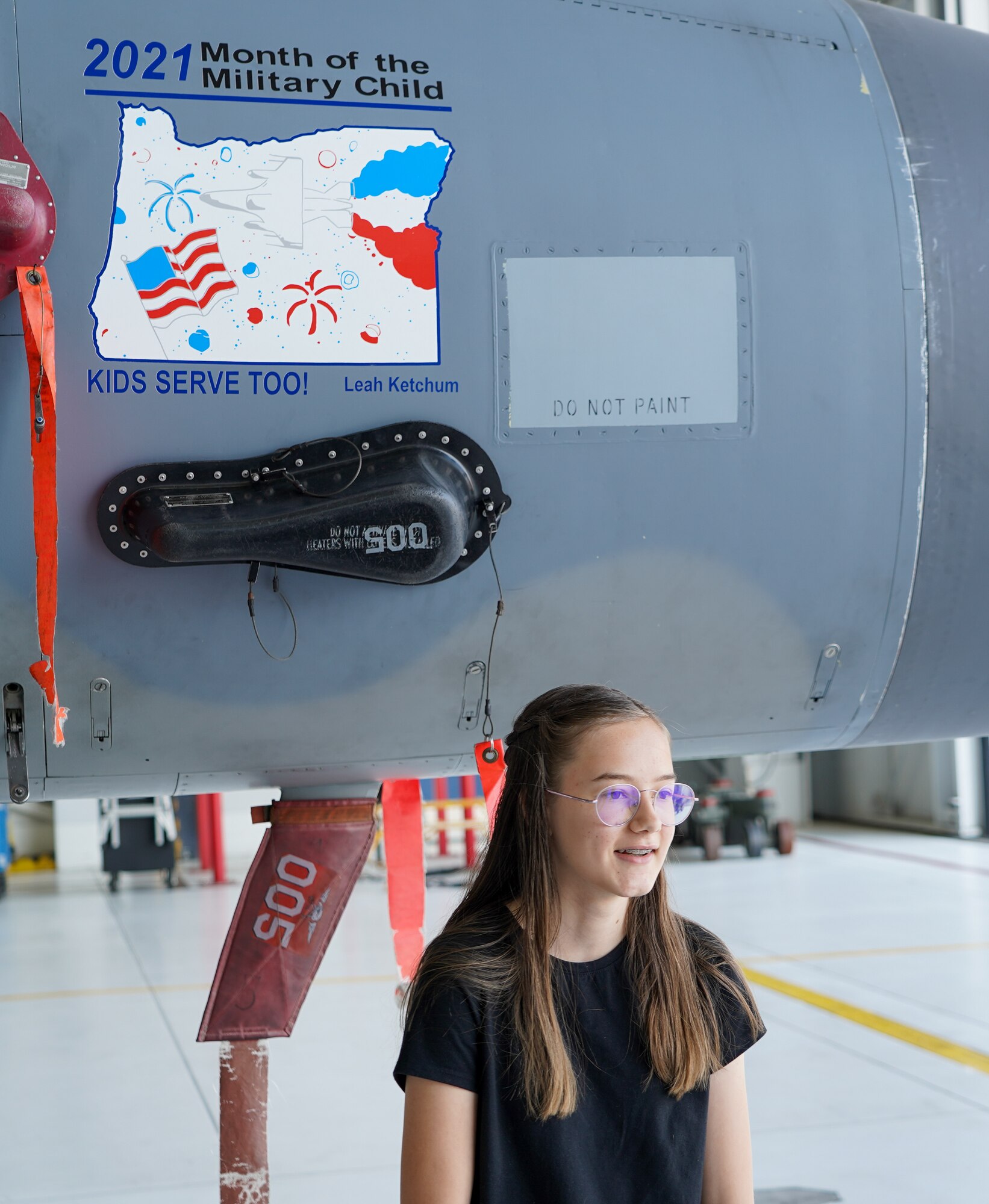 Leah Ketchum poses for a photo in front of a 142nd Wing F-15 Eagle that now displays her artwork on its nose on August 12, 2021 in Portland, Ore. The 142nd Wing and the 173rd Fighter Wing both held contests in support of Month of the Military Child in which each wing chose one winner to have their designs applied to fighter jets at their respective wings. (U.S. Air National Guard Photo by Staff. Sgt. Alexander Frank)