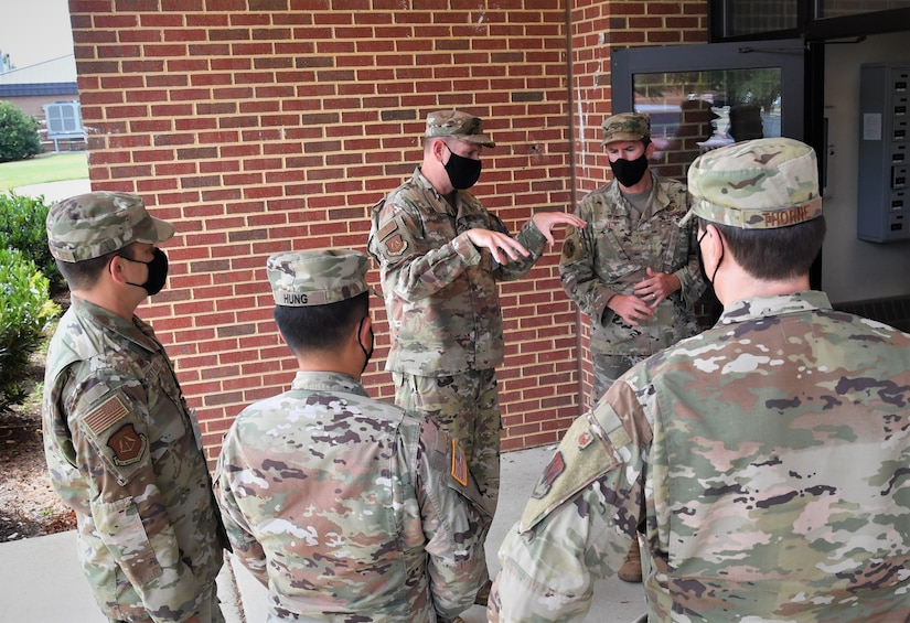 Group of Airmen stand in circle and talk.