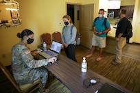 U. S. Army Spc. Karen Romo, a forward area support team member from 1st Infantry Division Sustainment Brigade, in-processes medical support team staff from Navy Medicine Readiness and Training Command Bethesda into a joint operations area Aug. 17, 2021, during the COVID response operations in Lafayette, Louisiana.