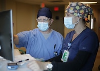 U.S. Navy Ensign Kyle Keeler, a registered nurse from Navy Medicine Readiness and Training Command Bethesda shadows Elise Gaudet, a civilian registered nurse at Ochsner Lafayette General Medical Center, to learn internal processes prior to his first shift during COVID-19 response operations in Lafayette, Louisiana, Aug. 19, 2021.