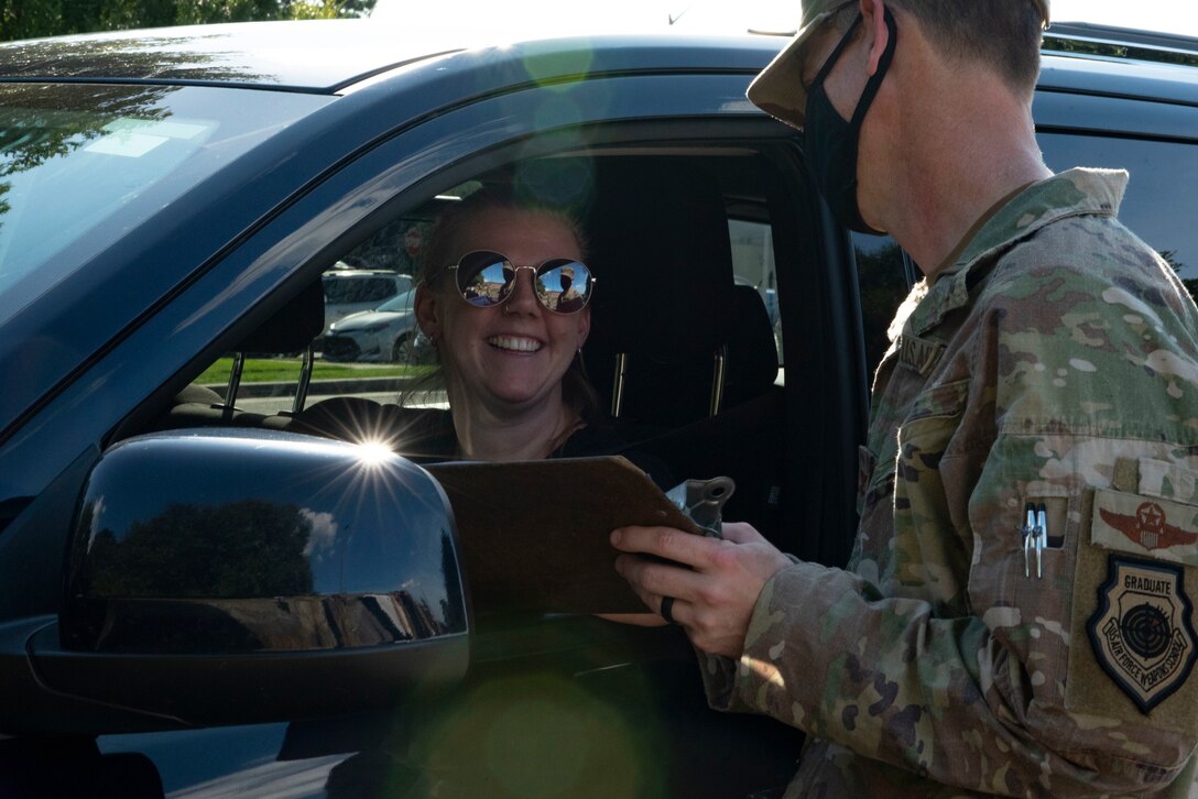 Photo of Airman taking a food order from person in their car