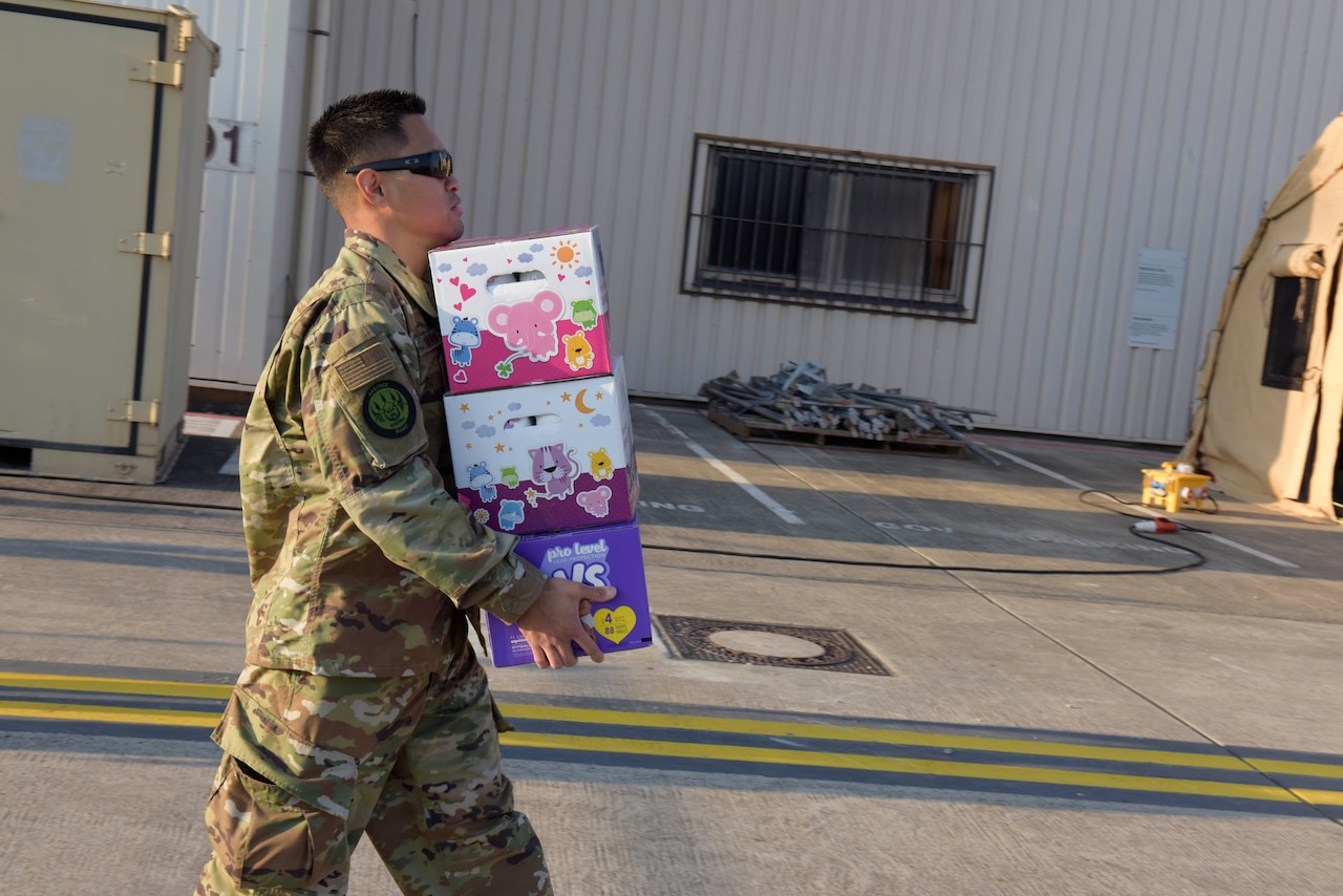 An aiman walks with a handful of boxes.
