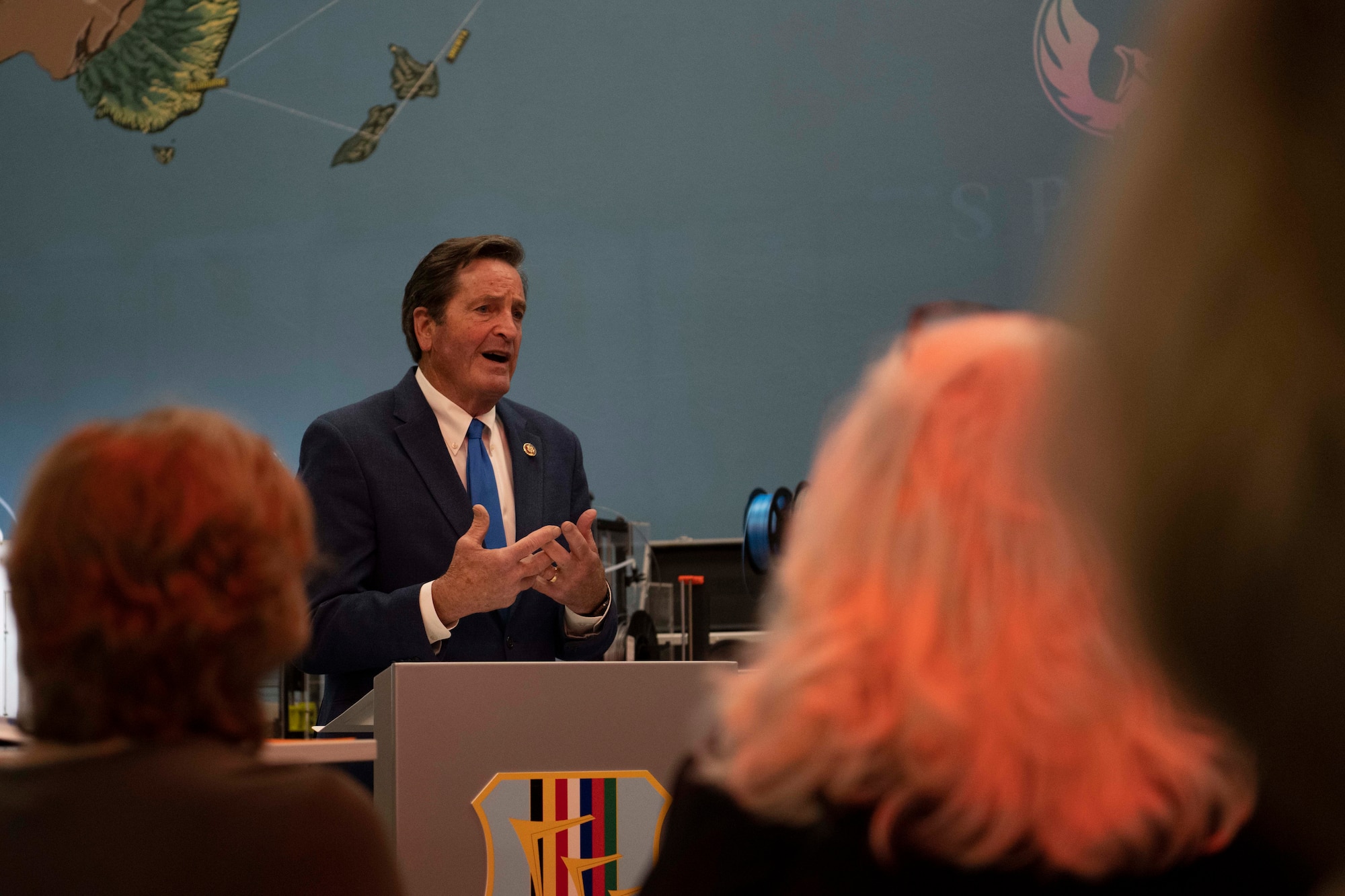 A man speaks at a podium in front of others